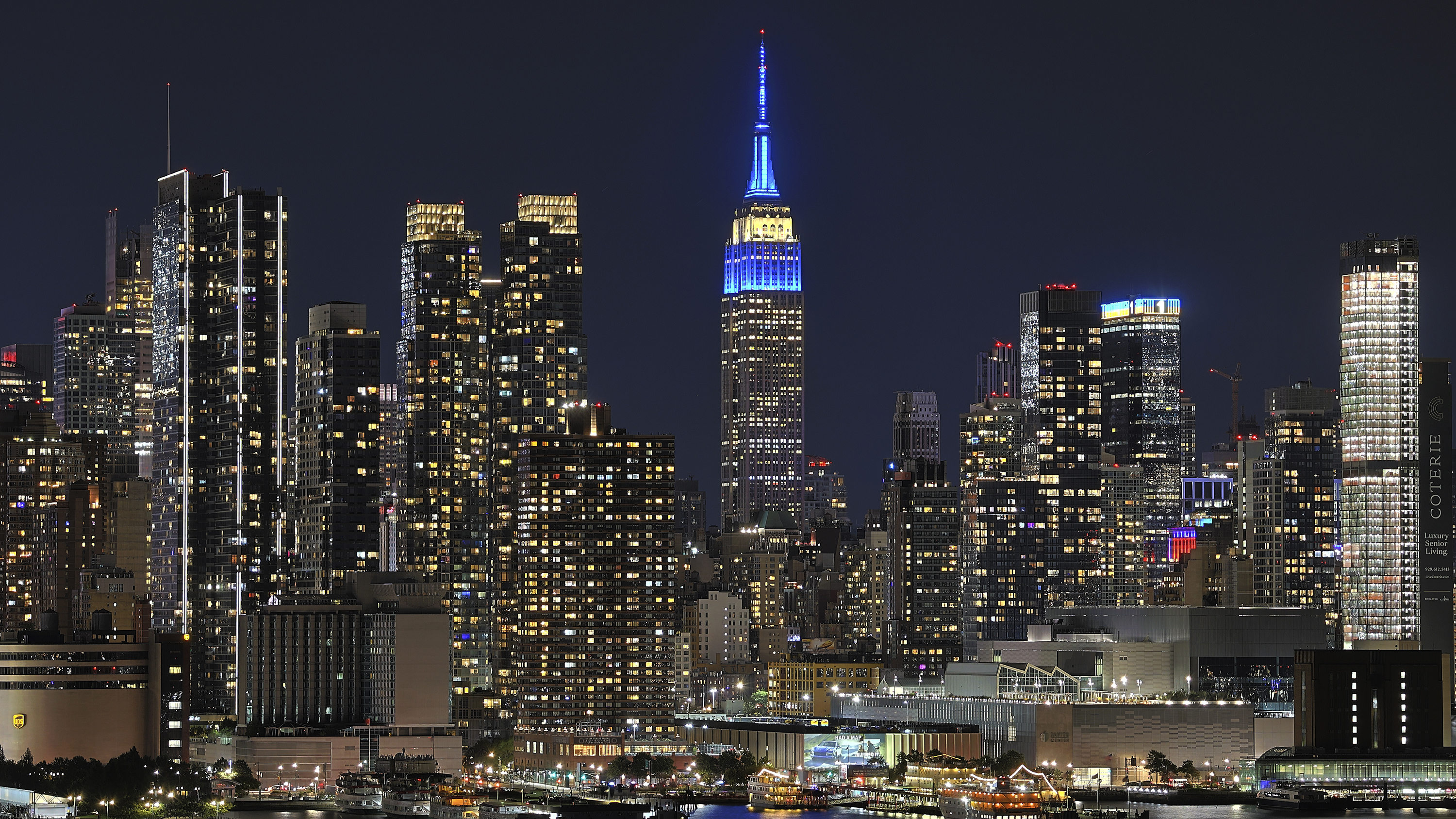 The Empire State Building is lit up in blue among the New York City skyline