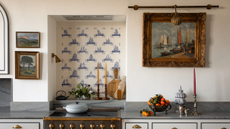 a kitchen with a small oven, decor on the countertops, and a vintage watercolor painting hanging on the wall 