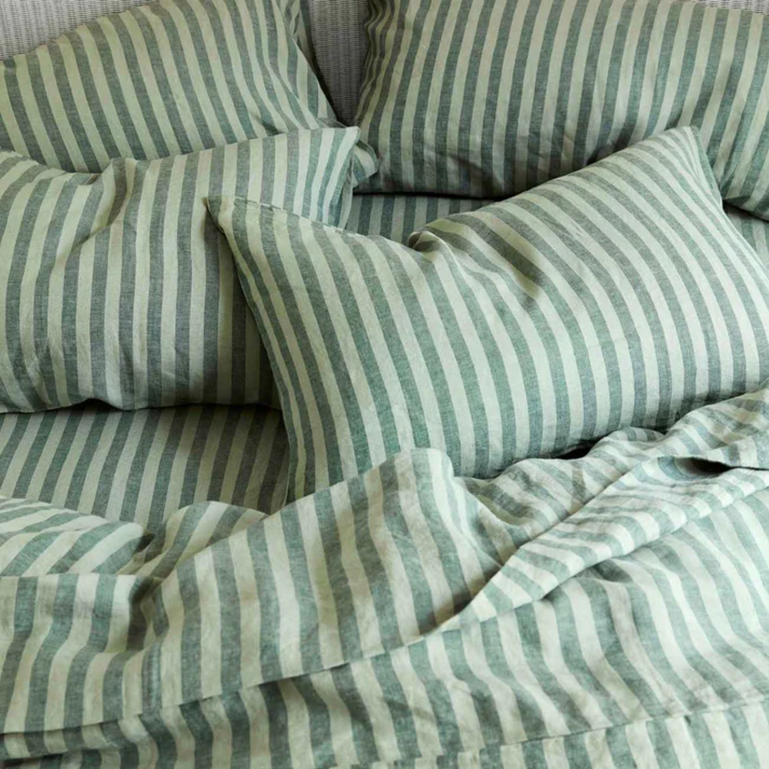 A striped green bedscape with a fitted sheet and four pillows