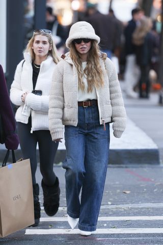 A photo of Sydney Sweeney topping her cream-colored knit puffer with a furry off-white bucket hat.