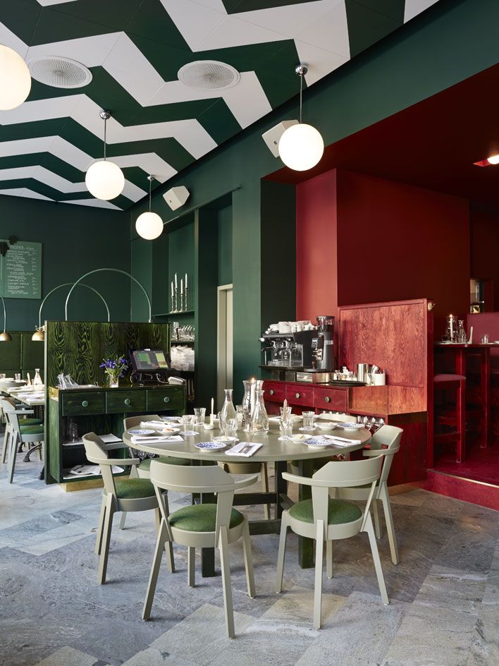 green &amp; red interior of Bar Central in Sweden which features a dark green &amp; white chevron patterned painted ceiling 