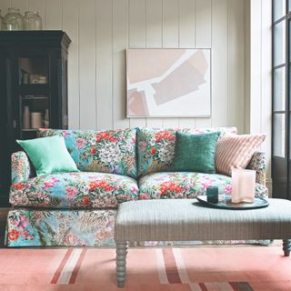 A living room with cream wall panelling and a floral-print sofa complemented by a pink rug