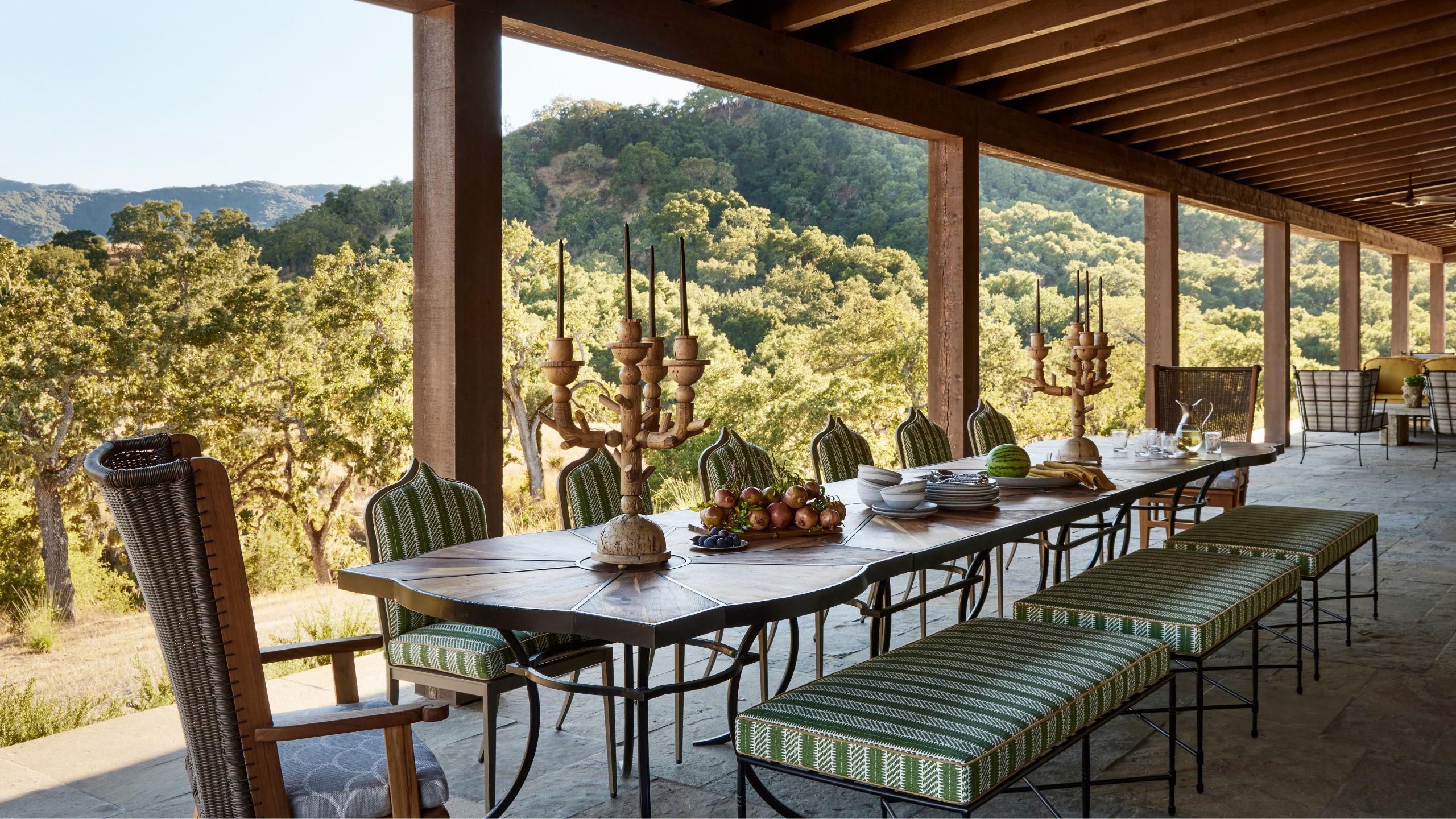 a large verdana off a ranch style home with wooden overhang and a carved antique table and chairs with green striped cushions