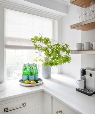 A kitchen nook used as a 'butler's pantry' painted white with wooden shelves