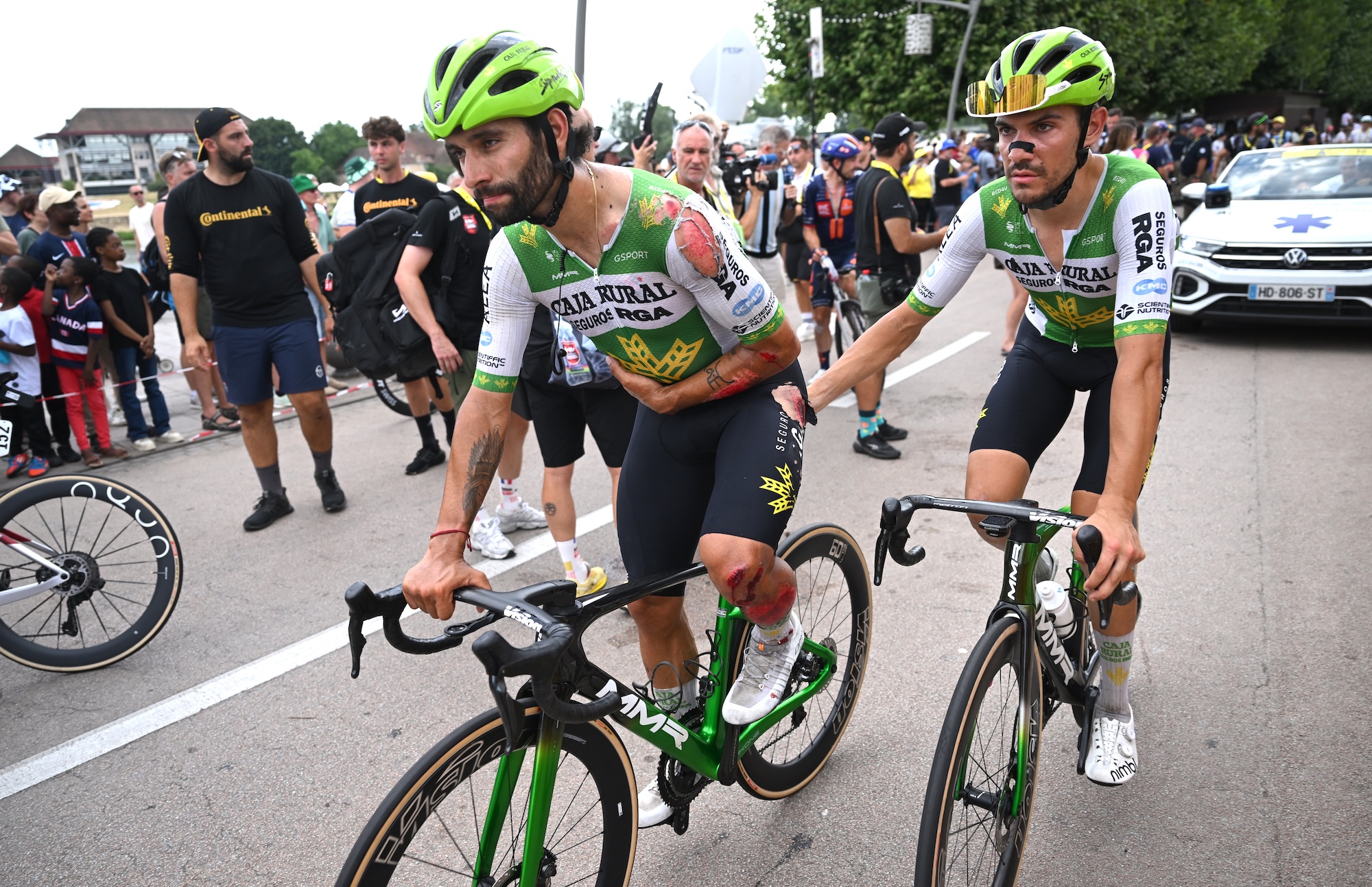 Gaviria holding his left arm to his chest as a teammate pushes him