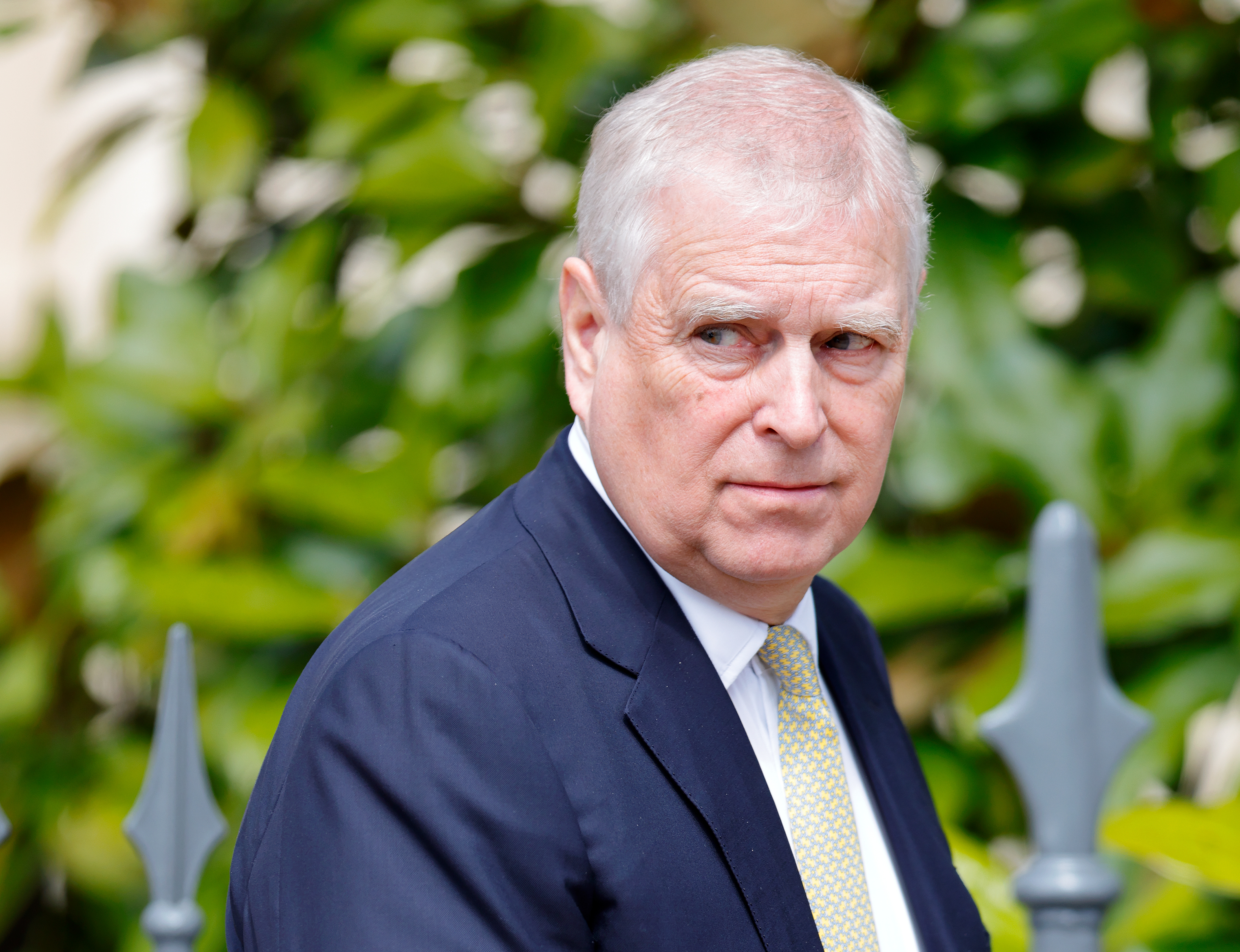 Prince Andrew wearing a blue suit and scowling