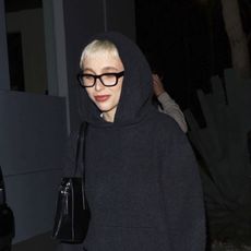 Emma Chamberlain wearing a gray knit set and slouchy black boots