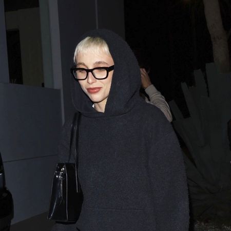 Emma Chamberlain wearing a gray knit set and slouchy black boots