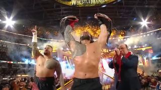 Roman Reigns holding up his titles after beating Cody Rhodes at WrestleMania 39