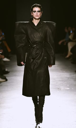 Model wearing exaggerated angular shoulder trench