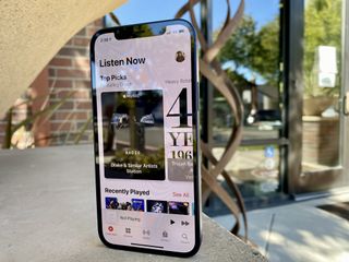 iPhone 12 showing Apple Music with a sculpture in the background
