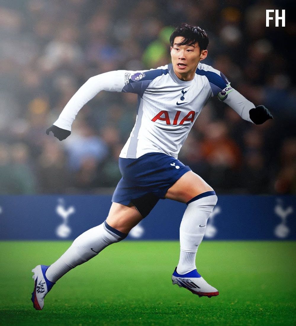 A footballer wearing a white shirt with navy sleeves and shorts with white socks is running.