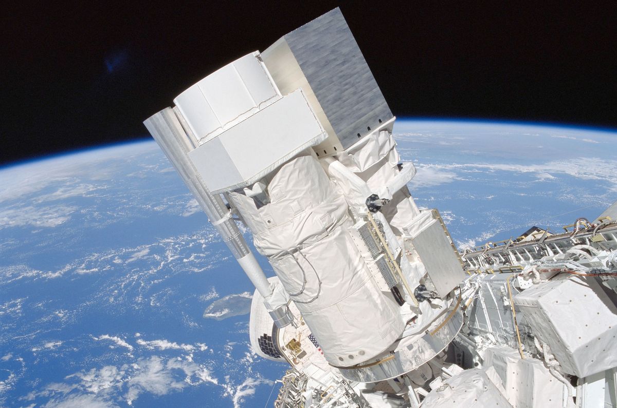 The Astro-1 payload is seen backdropped against the blue and white Earth in this scene photographed through the space shuttle Columbia&#039;s aft flight deck windows during the STS-35 mission in December 1990. The hardware, which flew again on STS-67 in 1995, is now restored for public display.