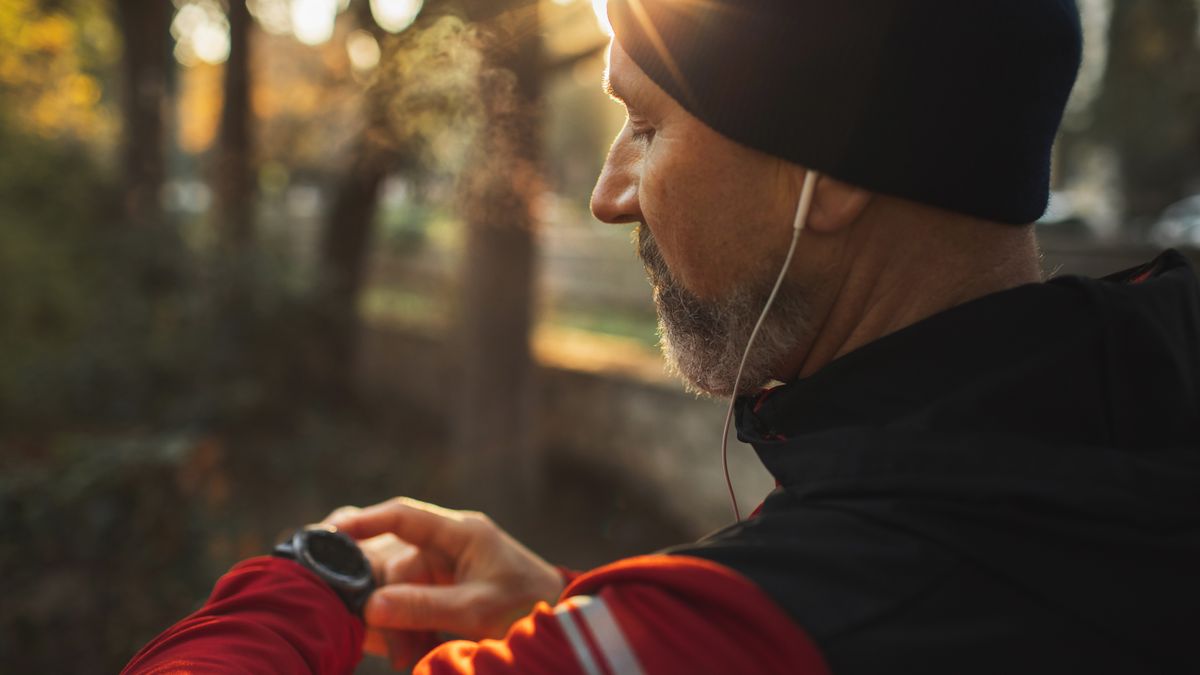 Man checking sports watch while running in wood