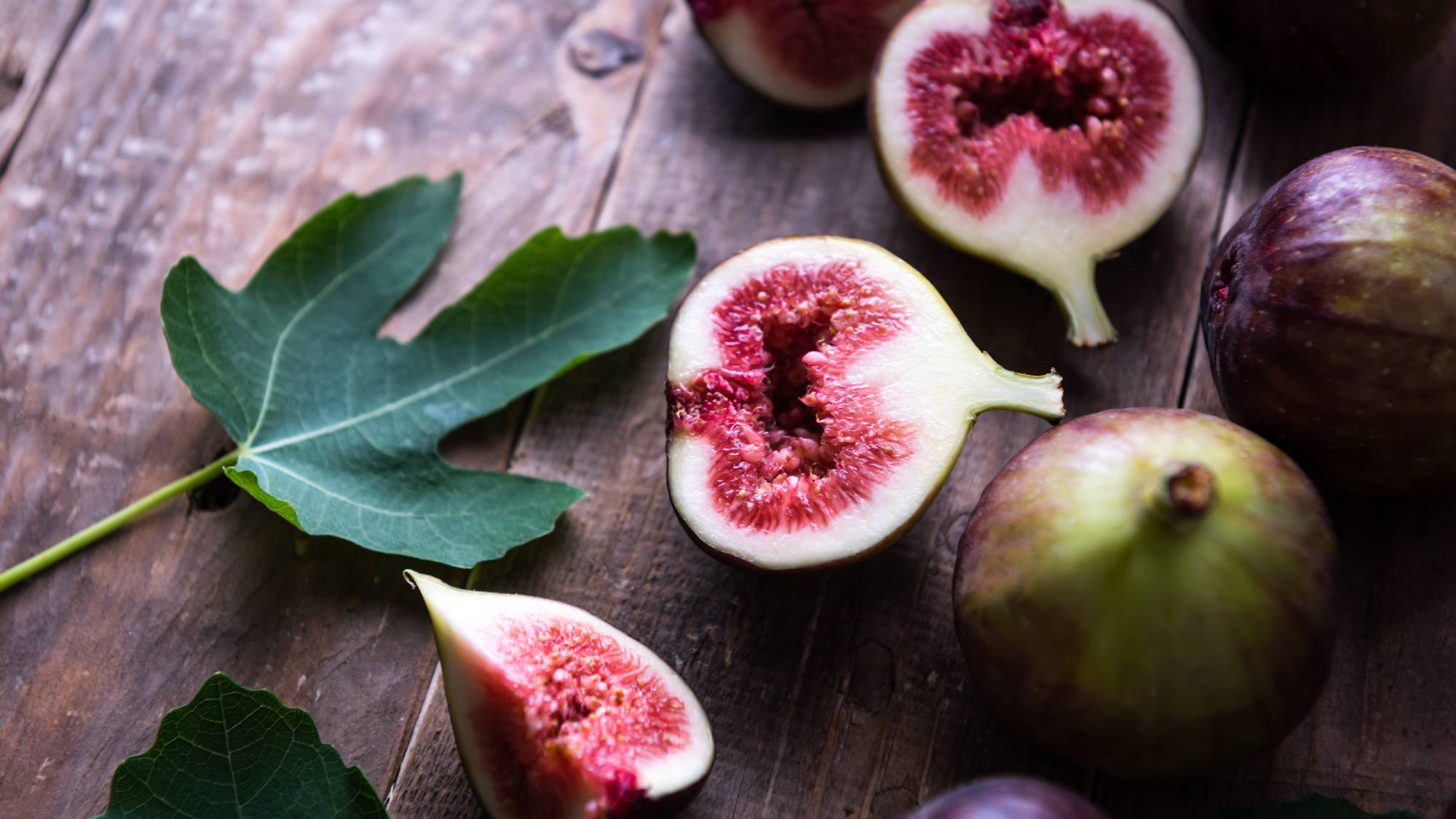 Sliced figs on a wooden table with leaf