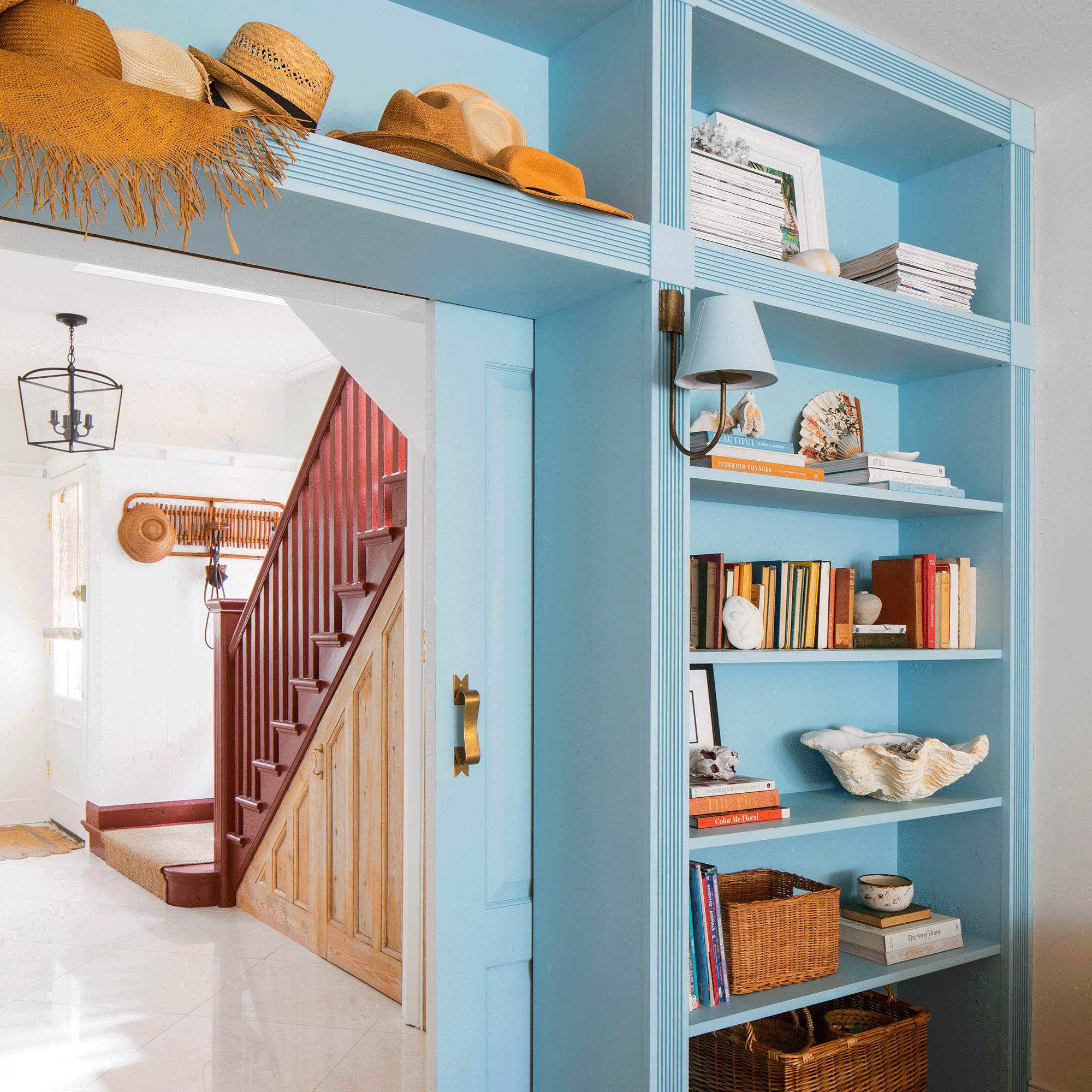 a blue wall of built-in storage with sliding pocket doors leading out into a hallway with a red stairwell