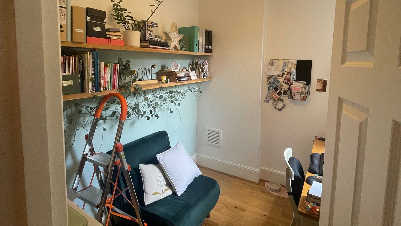 Looking through the door into a small room used as a home office with cluttered wall shelves