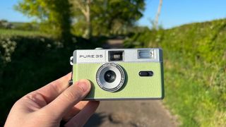 Hand holding a green film camera.