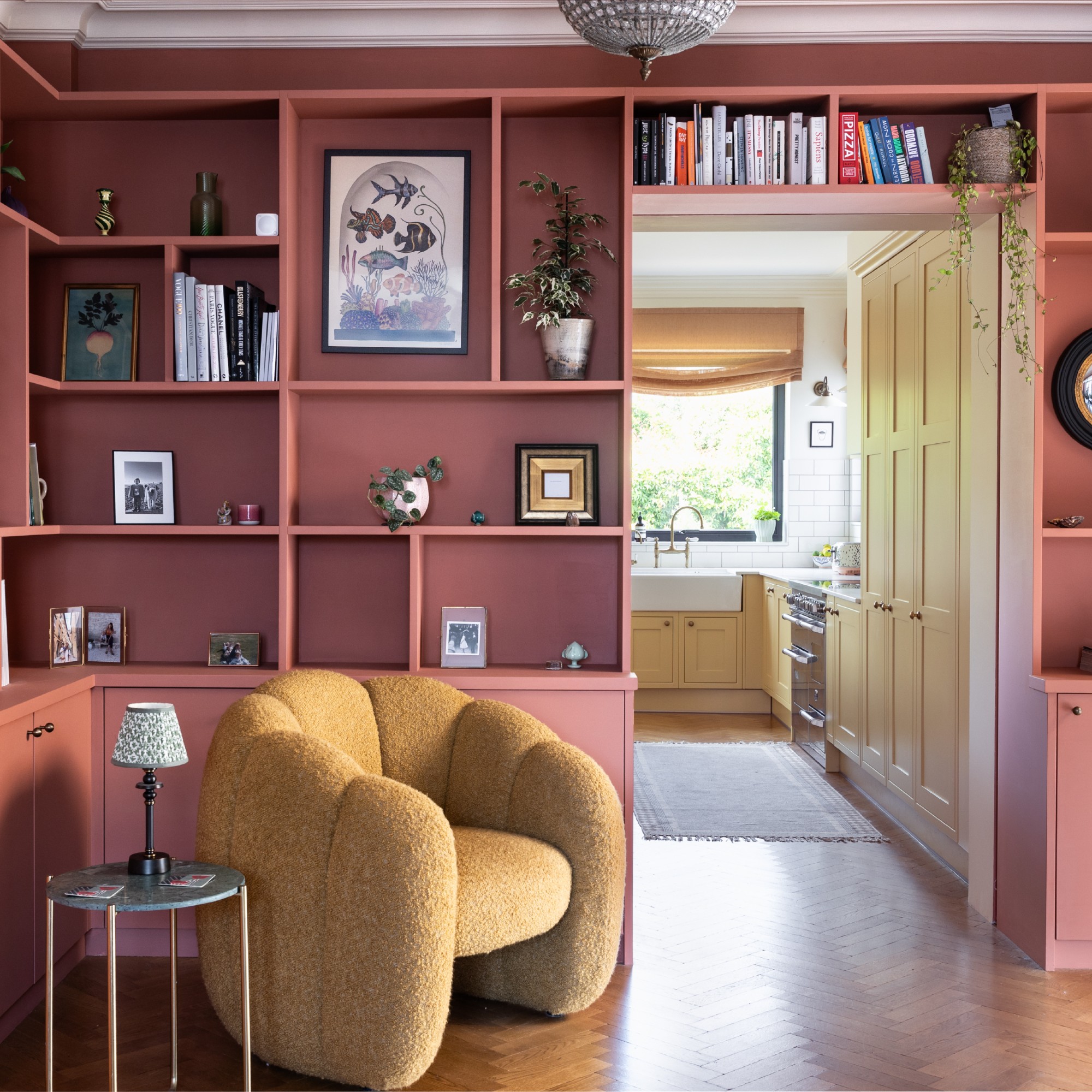 A living room with built-in shelving painted deep pink filled with curated decor