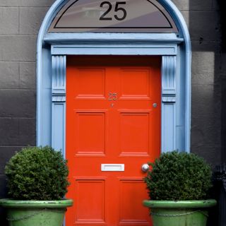 front door colour mistakes, red front door with pale blue painted surround, black numbers, matching planters