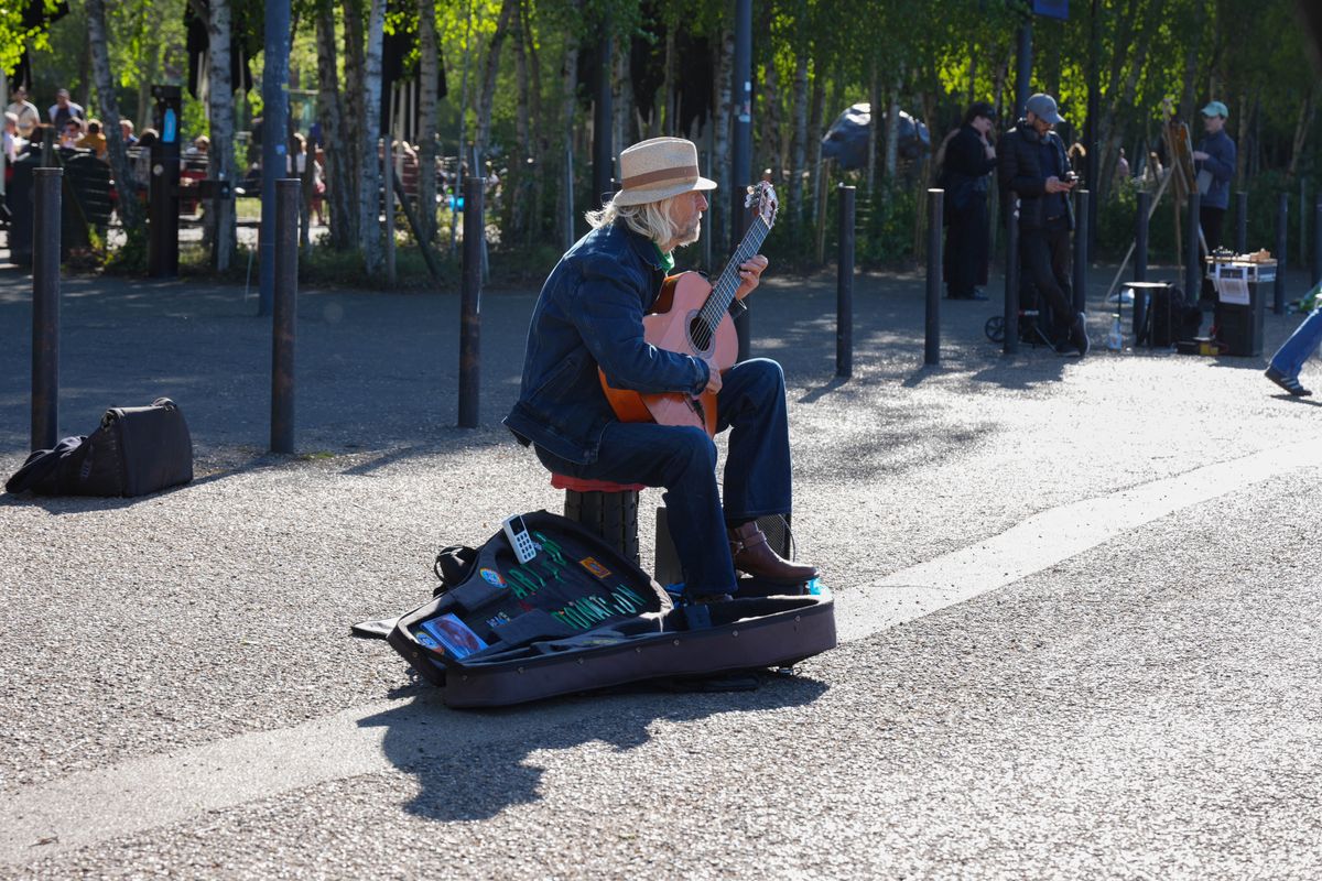 Street guitarist performing on the South Bank in bright sunlight.