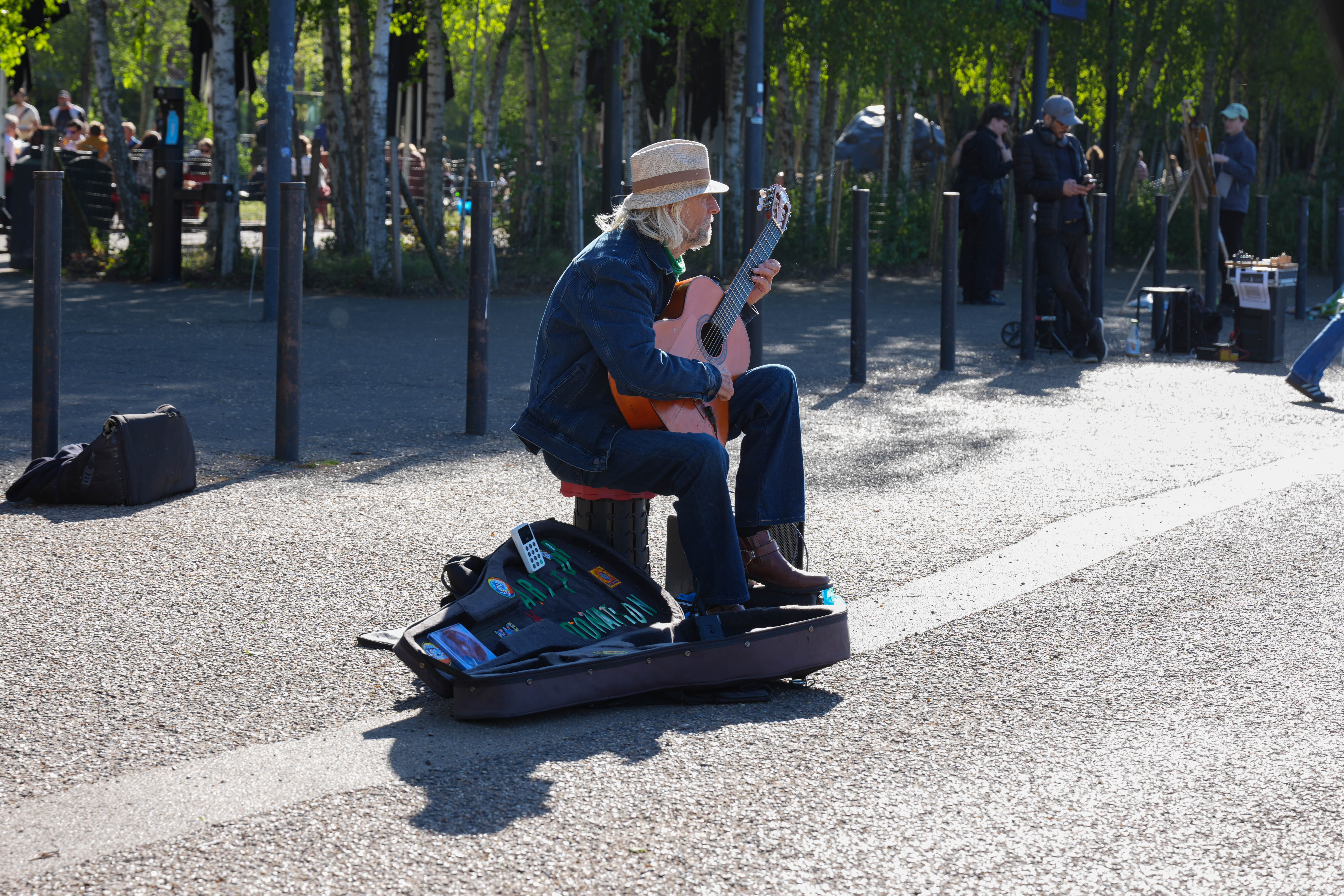 Street guitarist performing on the South Bank in bright sunlight.