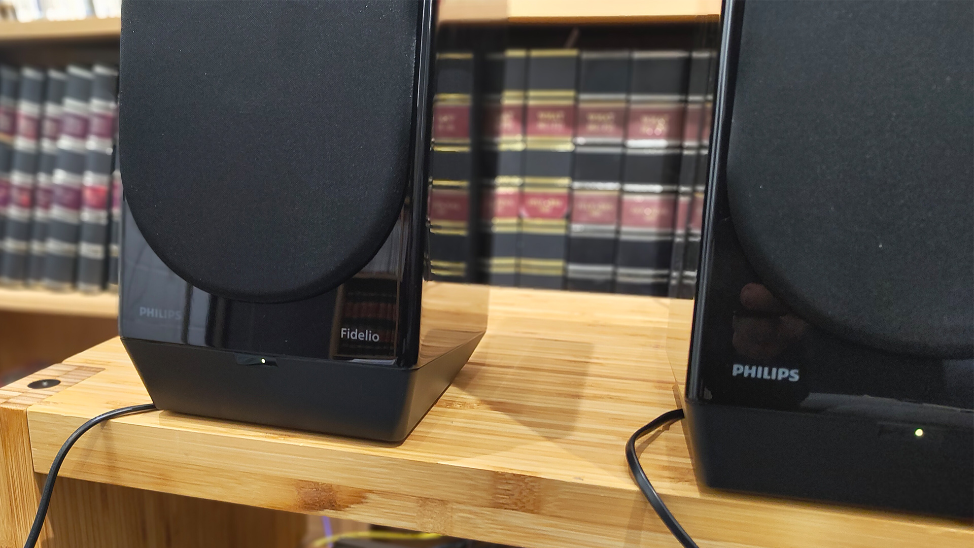 Philips Fidelio FA3 desktop speakers on wooden hi-fi rack in front of bookcase with grilles attached