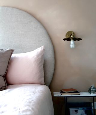 Neutral circular headboard in front of pale pink bedroom wall