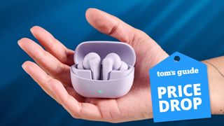 The JLab Go Pods ANC earbuds held in-hand against a blue background