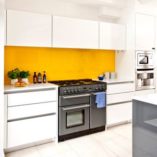 White kitchen with bright yellow splashback behind range cooker