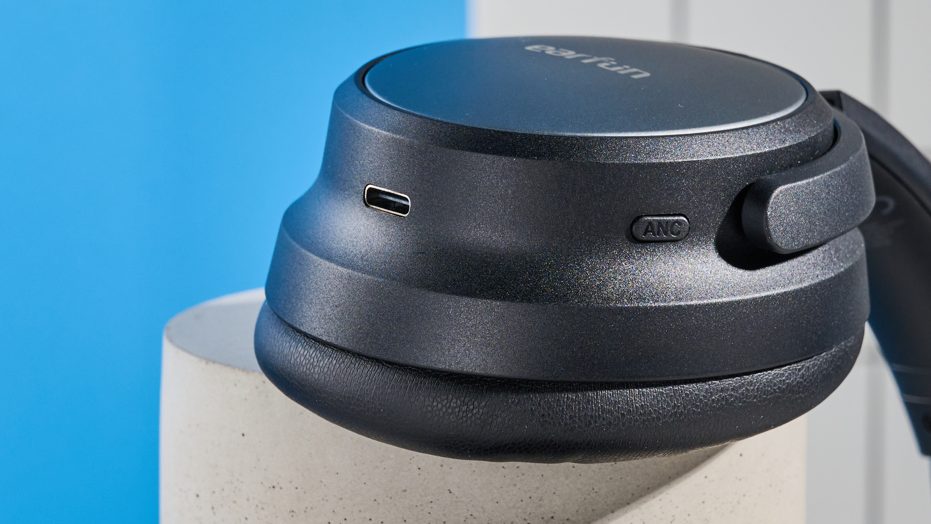 the earfun tune pro headphones, in black, with soft pleather cups, and gray cups, photographed against a blue background