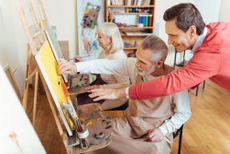 HMDR6C Overjoyed artist helping elderly man in painting studio