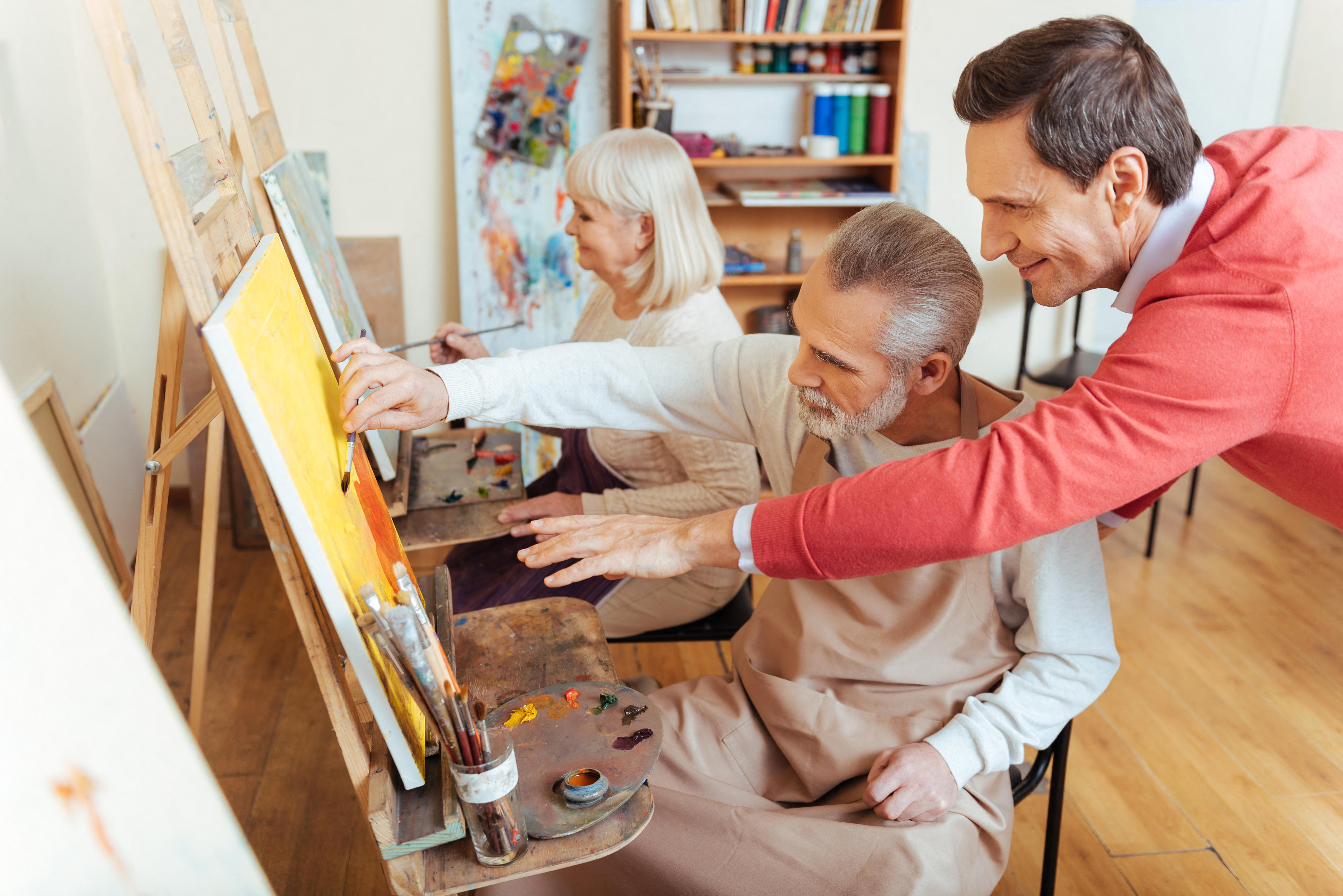 HMDR6C Overjoyed artist helping elderly man in painting studio