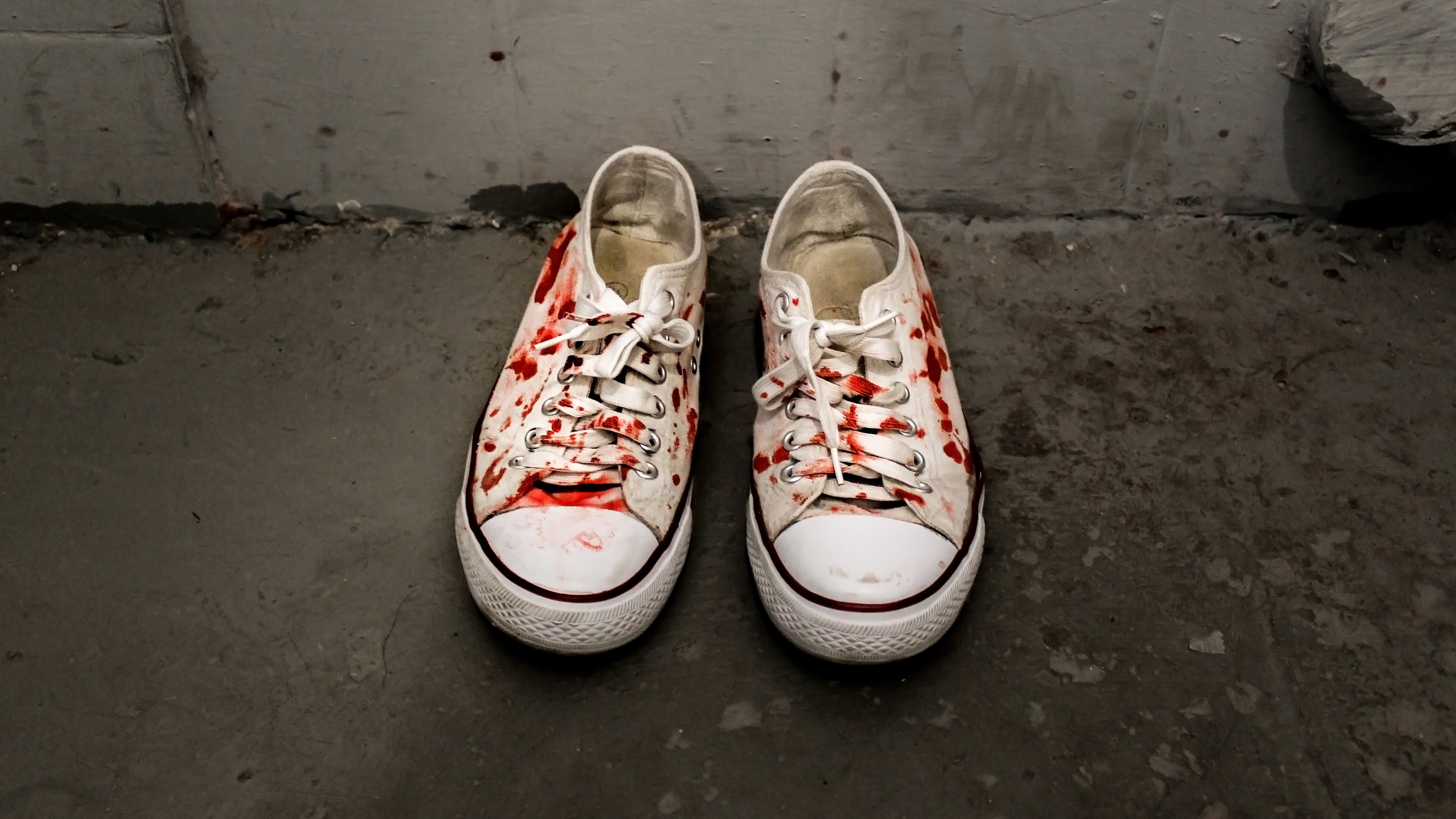A pair of white canvas shoes with fake blood splattered on them