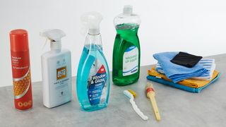 Various cleaning products and tools on a grey surface