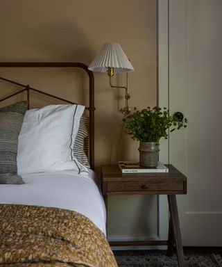 guest bedroom with grasscloth walls, mustard patterned throw and iron bed