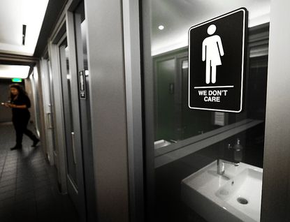A bathroom sign reads "We don't care" in reference to gender.