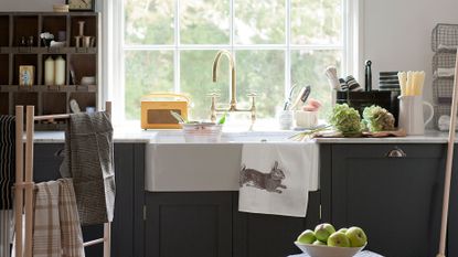 Utility room storage ideas showing a large sink under a period window with a shelving unit and cabinets