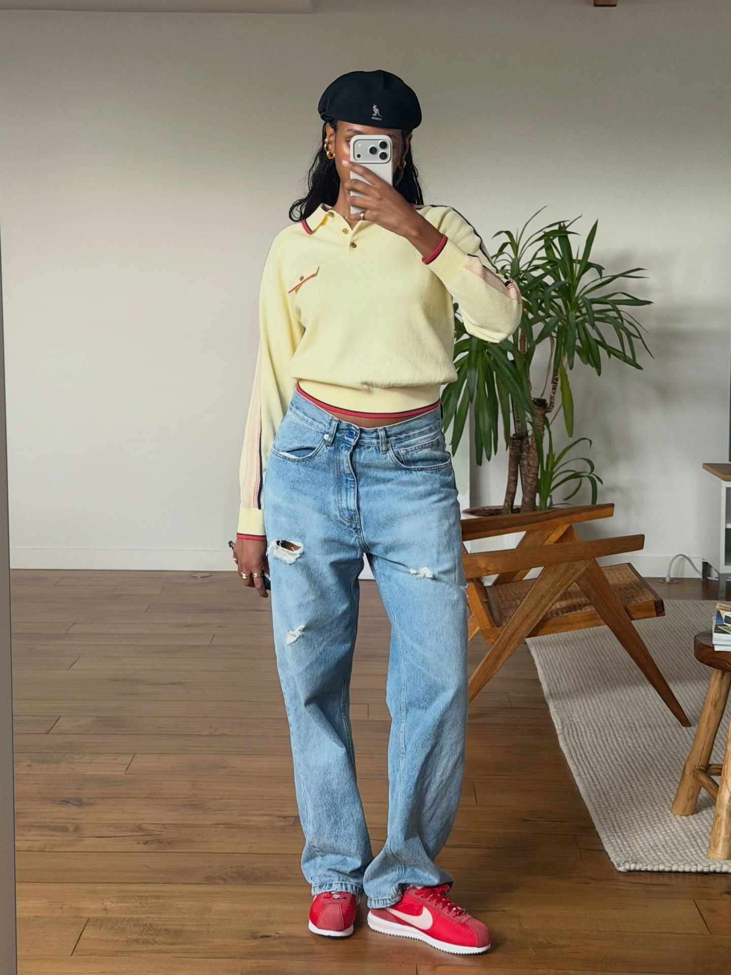 Claire wears a yellow sweater, ripped jeans, and red sneakers.