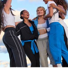 A group of women wearing Athleta activewear and cheering