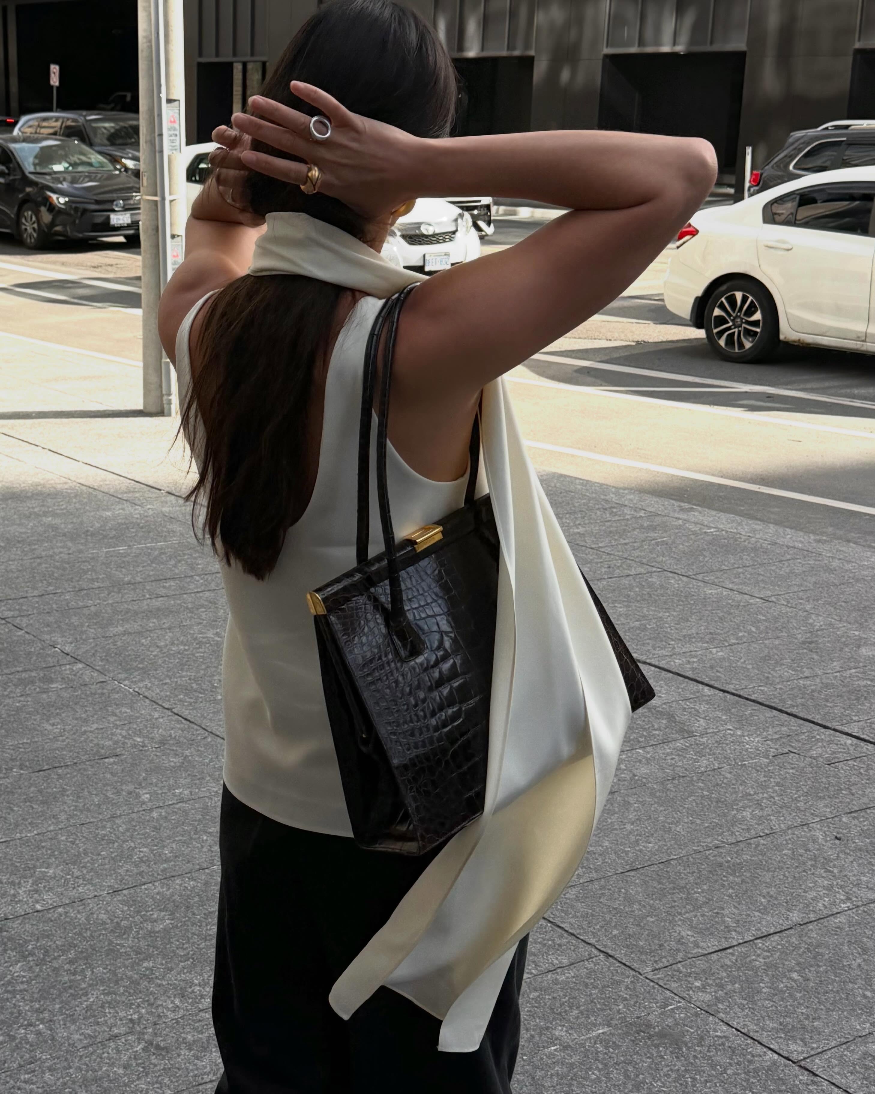 Creator @sasha.mei wearing a cream silk top with a black handbag