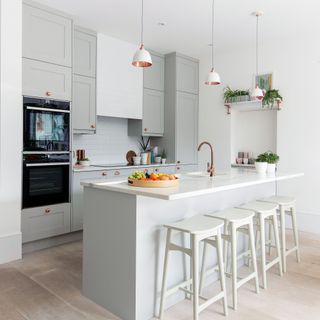 White kitchen with island, pendant lighting and pale grey cabinetry