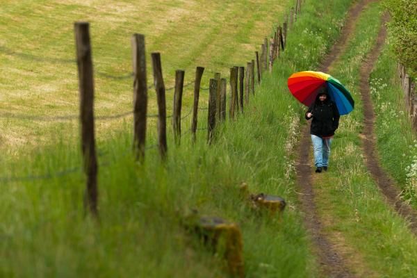 A specator with a colorful umbrella watches the juniors