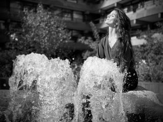 Model posing in front of jets from a water fountain outside on an Apple iPhone 16