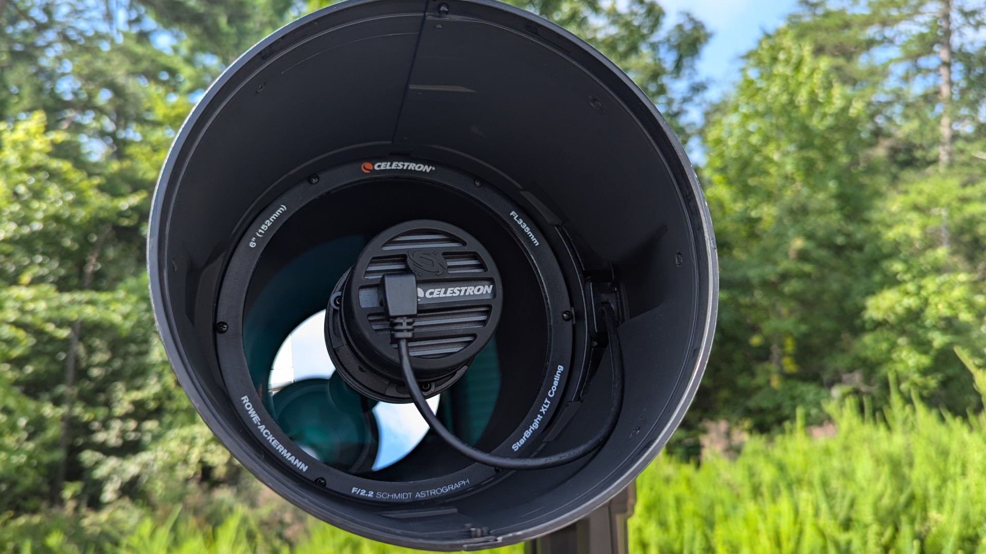 um telescópio preto e branco em um campo com árvores atrás dele