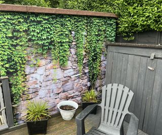 A garden shower curtain with a stone wall and ivy motif attached to a shed in a garden