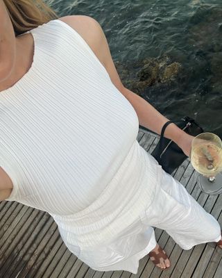 Kristen Nichols wearing an all-white outfit with Hermes Oran sandals