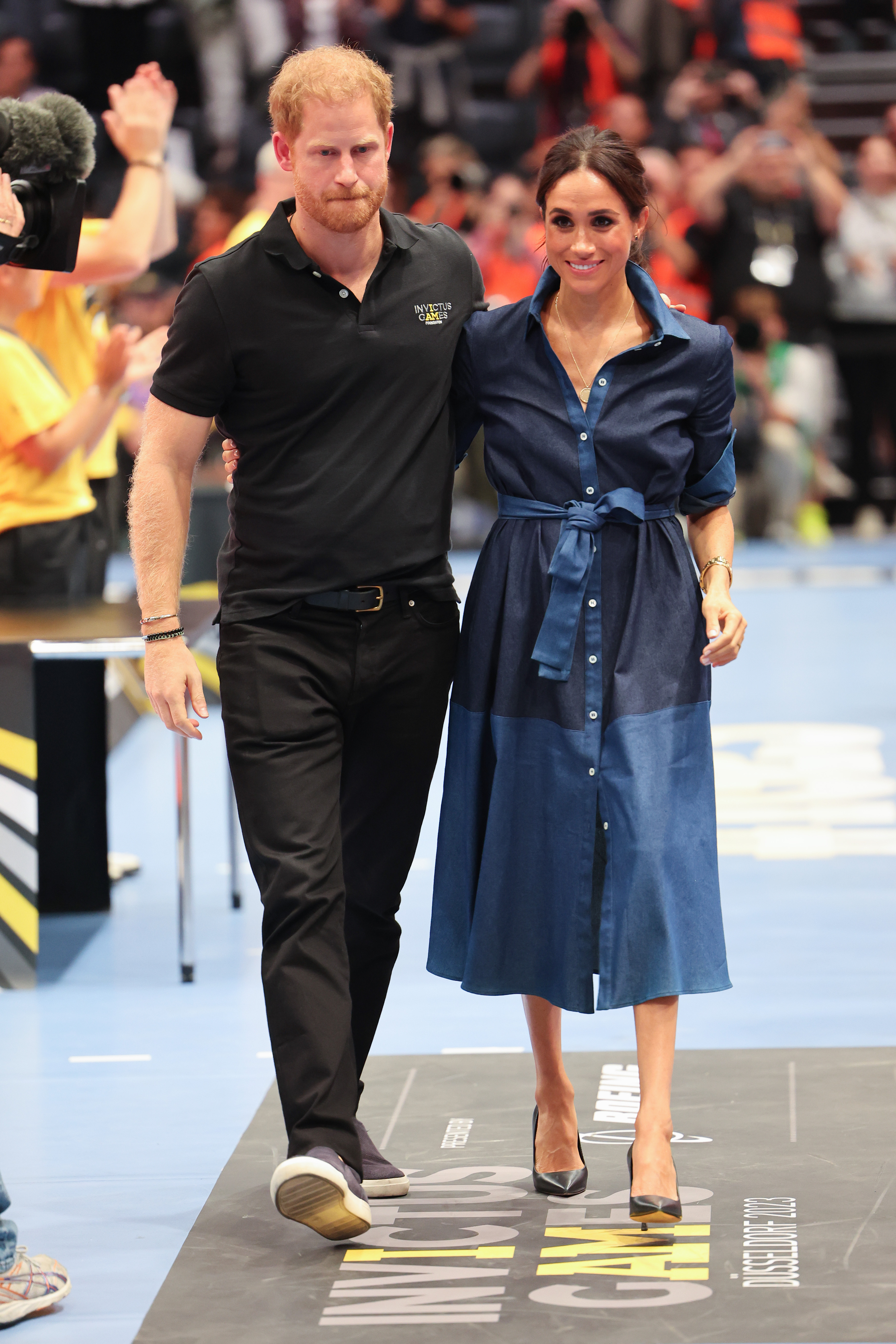 Prince Harry wears sneakers with an all-black outfit, Meghan Markle wears a denim dress and black pumps