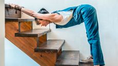 Woman using stairs to stretch. She is folded at her hips with her hands resting on a higher step on the stairs
