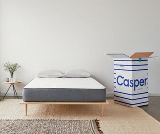 Casper mattress against a white wall beside a Casper delivery box.